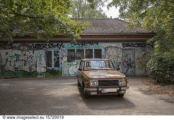Germany  Berlin  Brown vintage car parked in front of building covered in graffiti