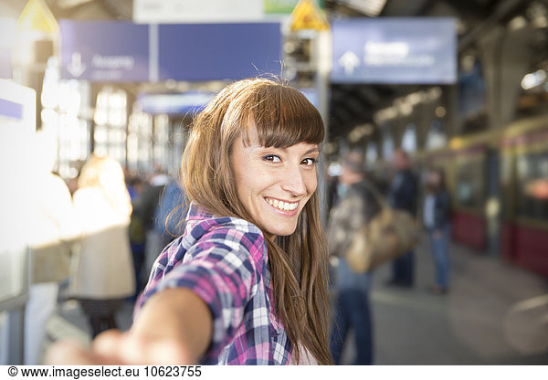 Germany  berlin  portrait of smiling young woman holding hands at platform