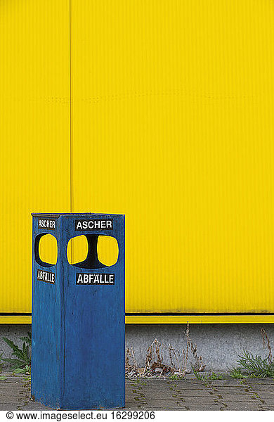 Germany  blue ashtray and waste bin in front of yellow facade
