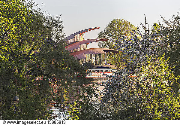 Germany  Brandenburg  Potsdam  Cherry blossoms blooming on bank of Havel river with Hans Otto Theater in background