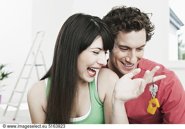 Germany Cologne Close up of young couple holding house keys in renovating apartment smiling