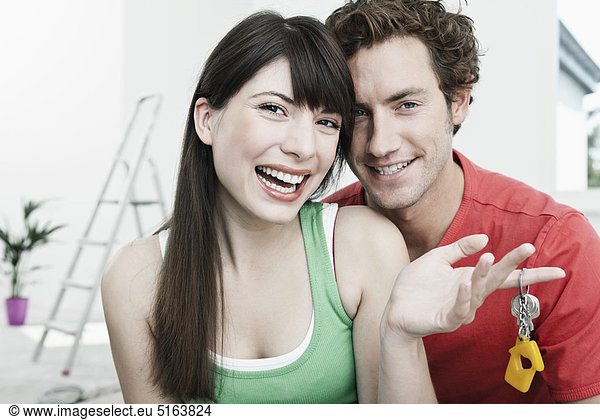 Germany Cologne Close up of young couple holding house keys in renovating apartment smiling