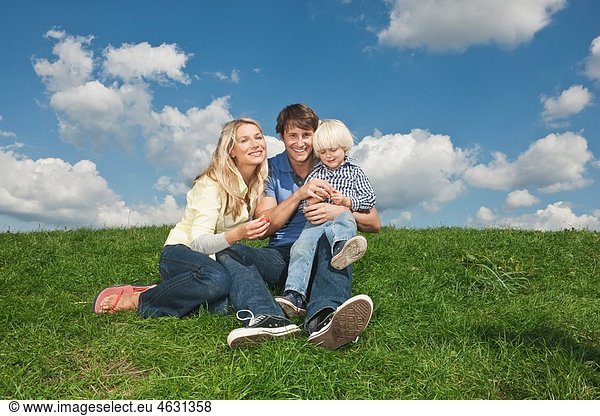 Germany  Cologne  Family sitting on grass  smiling