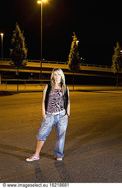 Germany  Cologne  Young woman standing on parking area hands in pocket  portrait