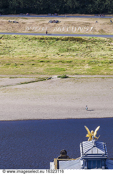 Germany  Dresden  People sitting at Elbe shore with text 'Not with Us'