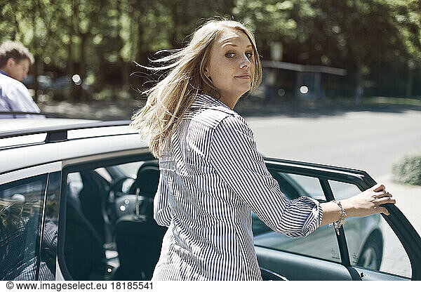 Germany  Duesseldorf  Young woman getting in to car