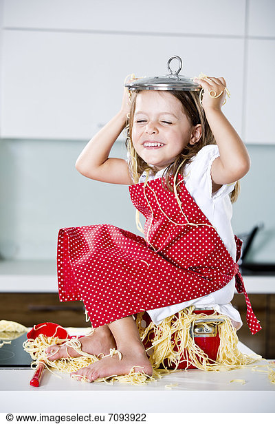Germany  Girl playing with spaghetti on kitchen worktop