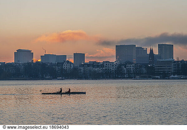 Germany  Hamburg  Alster Lake at dawn with city skyline and rowing boat in background