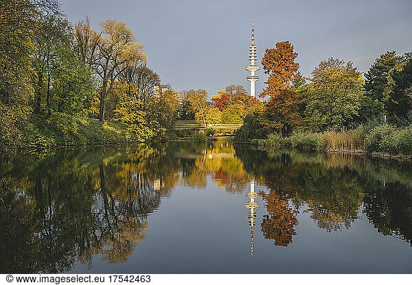 Germany  Hamburg  Autumn trees reflecting on surface of shiny lake in Wallanlagen park