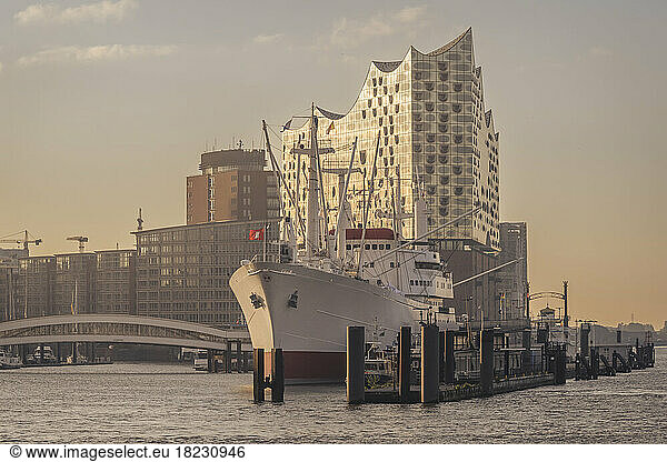 Germany  Hamburg  Cap San Diego ship moored in harbor at dusk with Elbphilharmonie in background