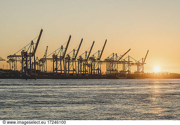 Germany  Hamburg  Container cranes along Elbe river at sunset