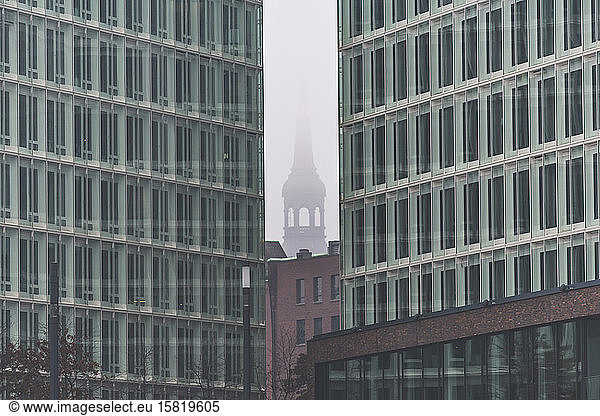 Germany  Hamburg  Fog shrouding tower of Saint Catherines Church seen between Ericusspitze buildings