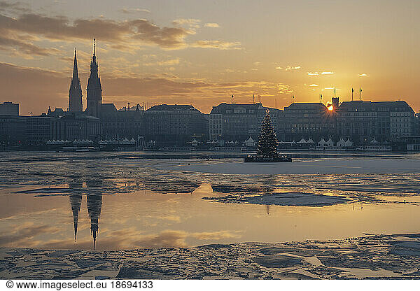 Germany  Hamburg  Ice floating in Alster Lake at sunset with city skyline in background