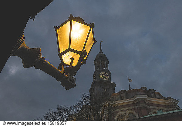 Germany  Hamburg  Low angle view of street light glowing against tower of Saint Michaels Church at night