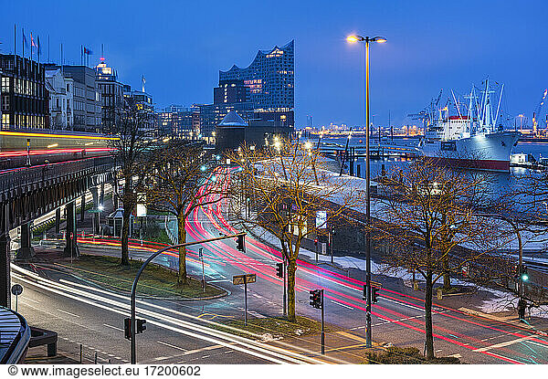 Germany  Hamburg  Vehicle light trails stretching along harbor street at dawn with Elbphilmarmonie in background