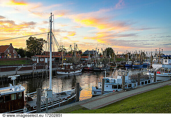 Germany  Lower Saxony  Greetsiel  Fishing boats moored along town harbor at moody dusk