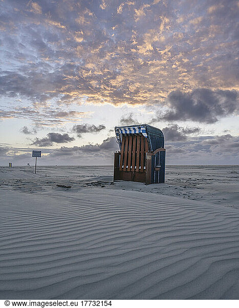 Germany  Lower Saxony  Juist  Hooded beach chair on empty beach at dusk