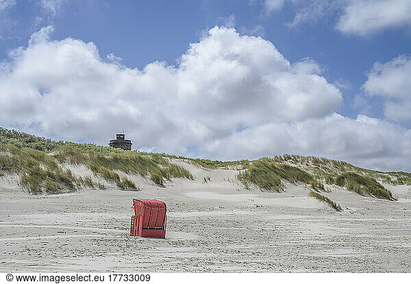 Germany  Lower Saxony  Juist  Hooded beach chair on empty beach with dunes in background