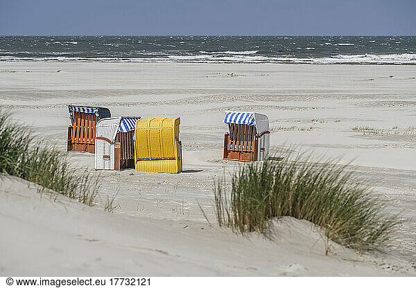 Germany  Lower Saxony  Juist  Hooded beach chairs on empty beach with clear line of horizon over North Sea in background