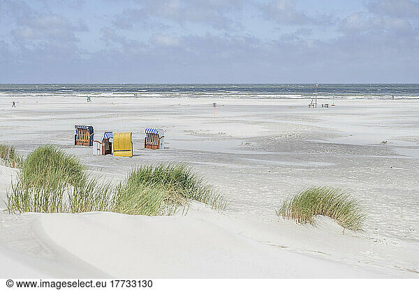 Germany  Lower Saxony  Juist  Hooded beach chairs on empty beach with clear line of horizon over North Sea in background