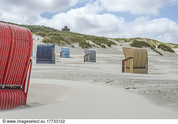 Germany  Lower Saxony  Juist  Hooded beach chairs on empty beach with dunes in background