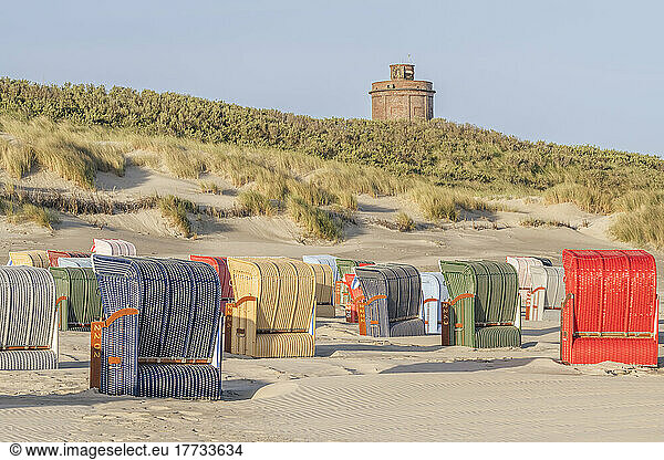 Germany  Lower Saxony  Juist  Hooded beach chairs on empty beach with water tower in background