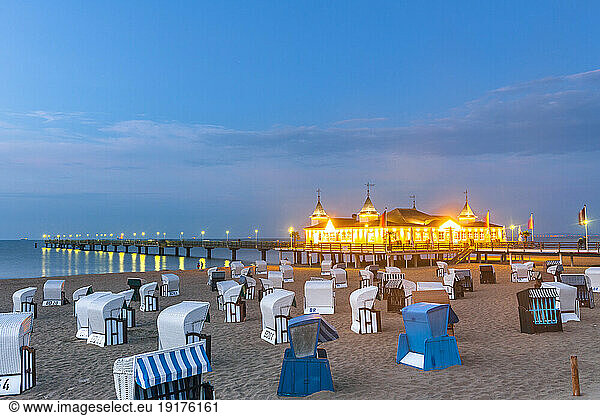 Germany  Mecklenburg-Vorpommern  Ahlbeck  Hooded beach chairs and illuminated pier at dusk