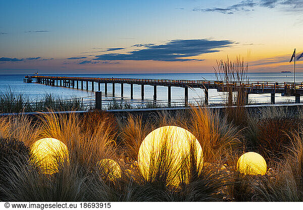 Germany  Mecklenburg-Vorpommern  Binz  Glowing spheres on beach of Rugen island with Seebrucke Binz pier in background
