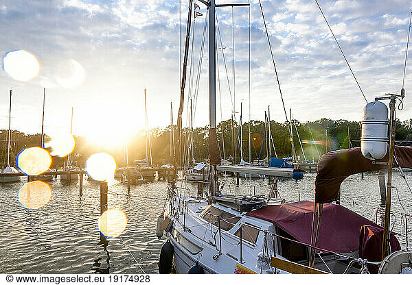 Germany  Mecklenburg-Vorpommern  Krummin  Boat moored in marina with setting sun in background