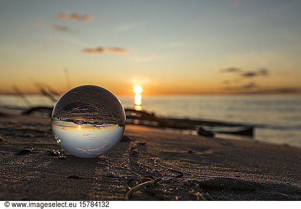 Germany  Mecklenburg-West Pomerania  Prerow  Shiny glass ball lying on sandy coastal beach at sunset