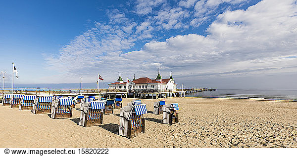 Germany  Mecklenburg-Western Pomerania  Heringsdorf  Hooded beach chairs on sandy coastal beach with pier in background