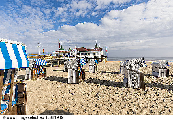 Germany  Mecklenburg-Western Pomerania  Heringsdorf  Hooded beach chairs on sandy coastal beach with pier in background