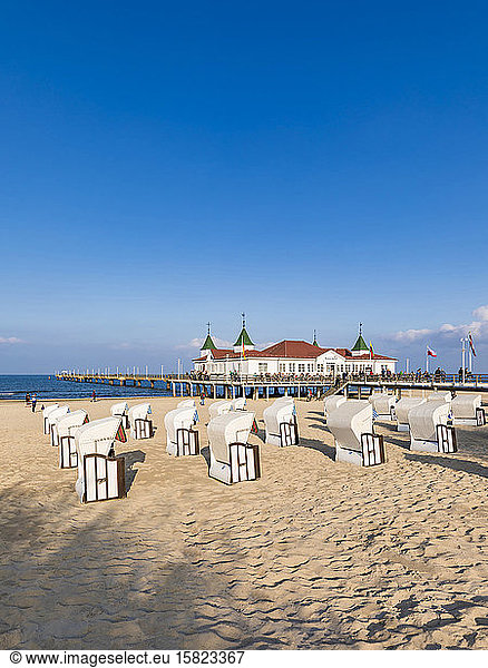 Germany  Mecklenburg-Western Pomerania  Heringsdorf  Hooded beach chairs on sandy coastal beach with pier in background