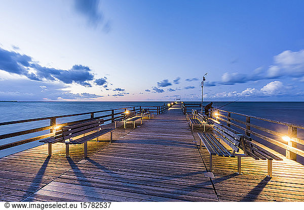 Germany  Mecklenburg-Western Pomerania  Prerow  Illuminated pier at dusk with clear line of horizon over Baltic Sea in background