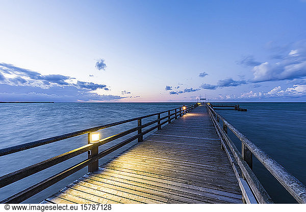 Germany  Mecklenburg-Western Pomerania  Prerow  Illuminated pier at dusk with clear line of horizon over Baltic Sea in background