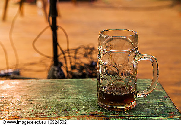 Germany  Munich  Oktoberfest  Beer jug on wooden table  stage equipment in background