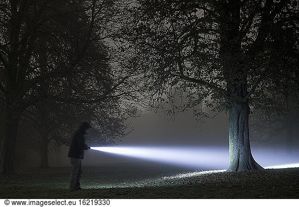 Germany  Munich  Young man with torch in foggy night