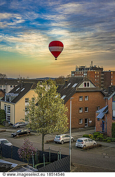 Germany  North Rhine Westphalia  Grevenbroich  Residential district at dusk with hot air balloon flying in background