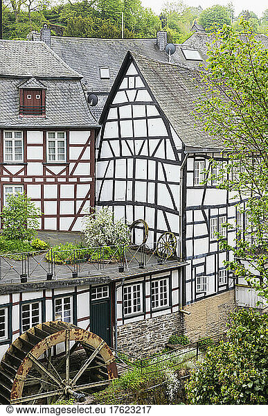 Germany  North Rhine-Westphalia  Monschau  Historic half-timbered townhouses with water wheel in foreground