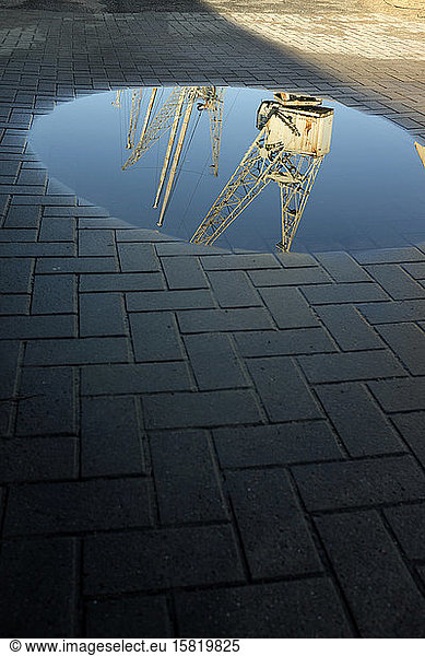 Germany  Old industrial cranes reflecting in shiny puddle