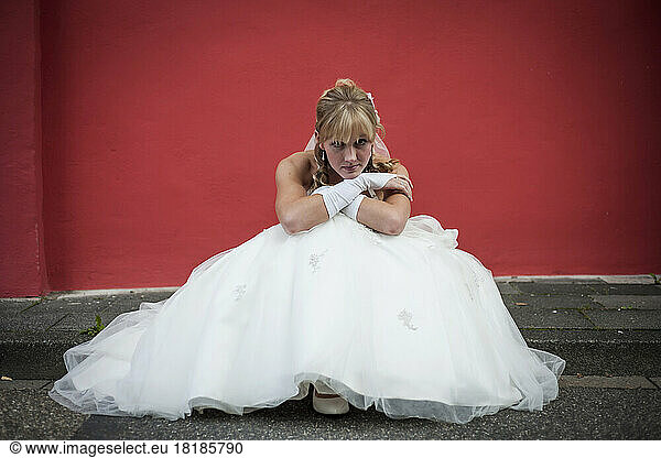 Germany  Rhineland-Palatinate  portrait of bride sitting on curb in front of red facade