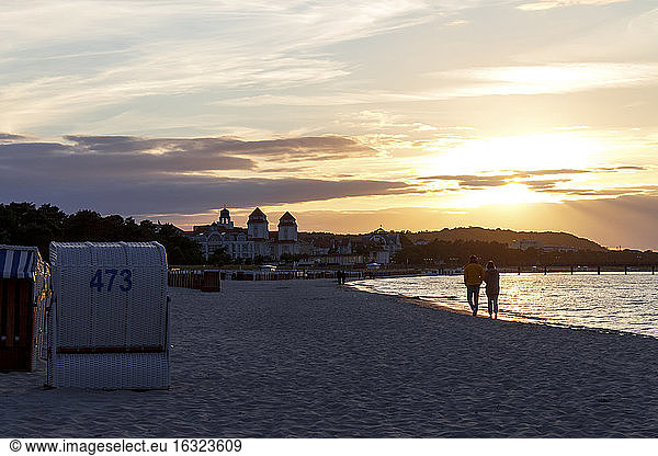 Germany Ruegen Binz people walking on beach at sunset