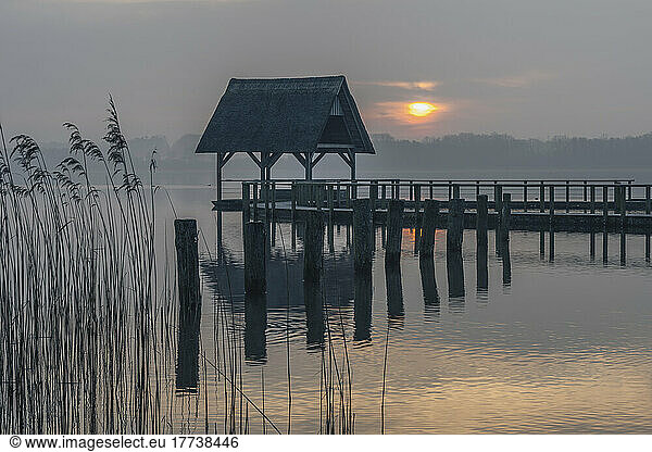 Germany  Schleswig-Holstein  Hemmelsdorf  Empty pier on shore of Hemmelsdorfer See at sunset