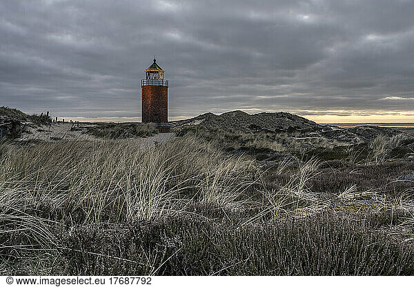 Germany  Schleswig-Holstein  Kampen  Grassy beach at cloudy dusk with Rotes Kliff Lighthouse in background
