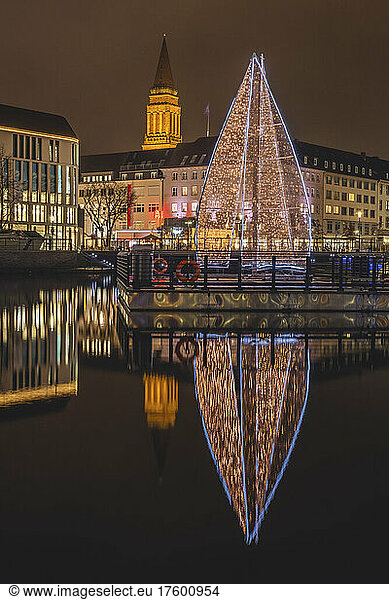 Germany  Schleswig-Holstein  Kiel  Large Christmas tree reflecting in city canal at night