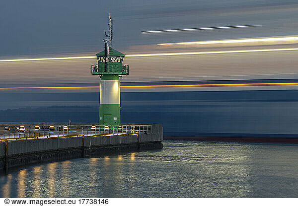 Germany  Schleswig-Holstein  Lubeck  Long exposure of ferry passing Travemunde lighthouse at dusk