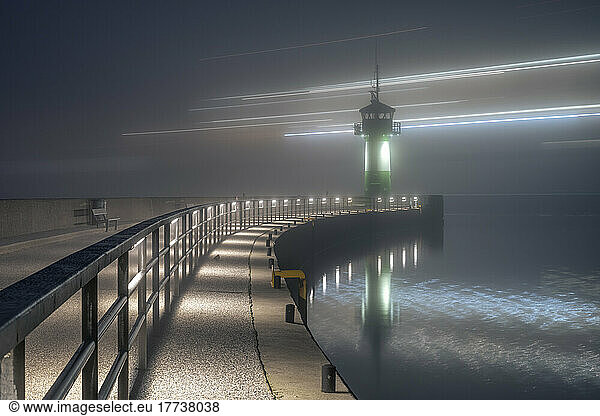 Germany  Schleswig-Holstein  Lubeck  Long exposure of ferry passing Travemunde lighthouse at foggy night