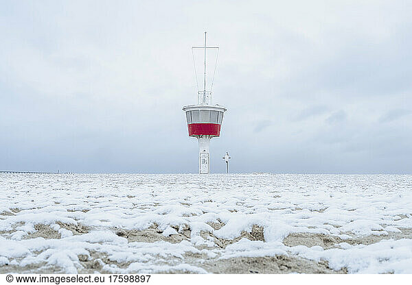 Germany  Schleswig-Holstein  Lubeck  Snow covered beach in Travemunde with lookout tower in background