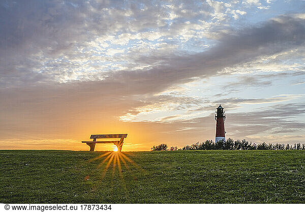 Germany  Schleswig-Holstein  Pellworm  Empty bench at sunset with Pellworm Lighthouse in background