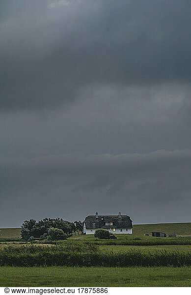 Germany  Schleswig-Holstein  Pellworm  Storm clouds over rural cottage